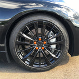 ColorLugs orange colored lug covers on black automobile wheel